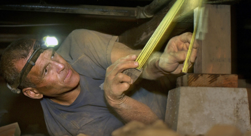 Greg Sylvis examines the foundation under a house.